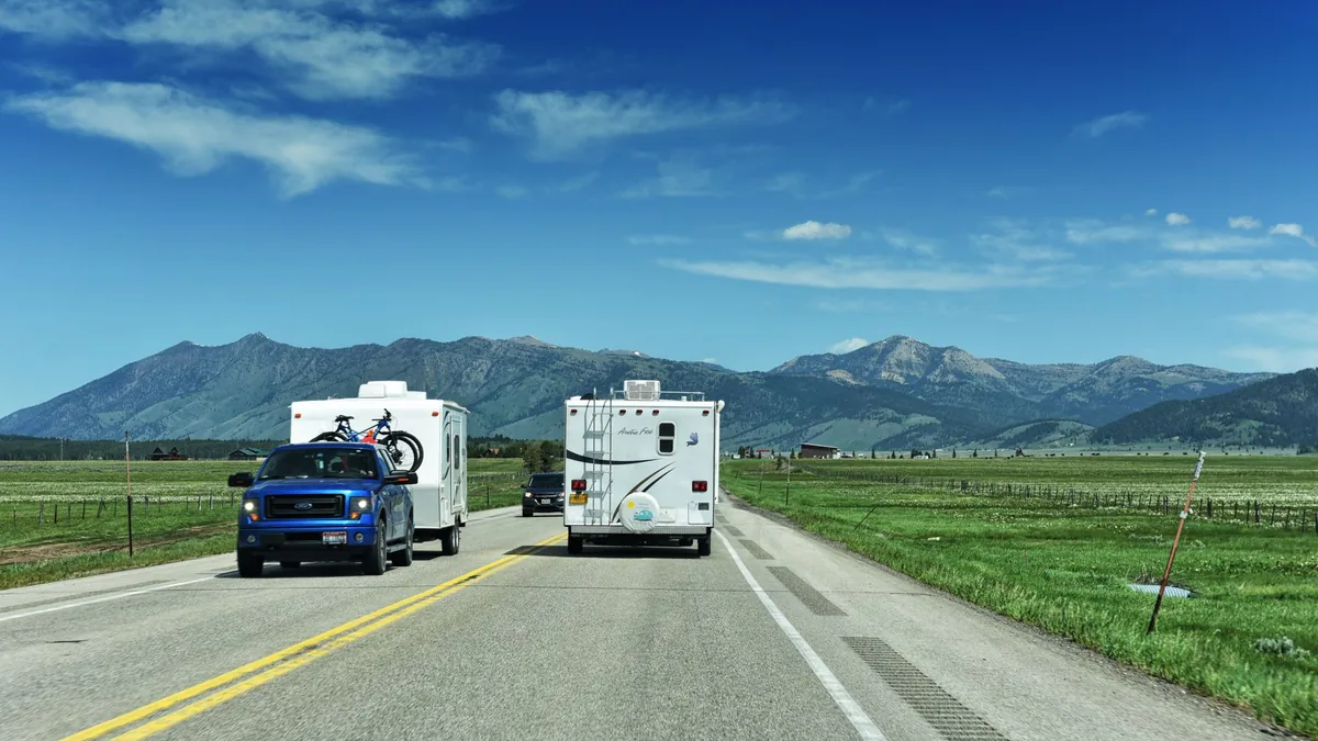 Two motorhomes travelling a highway through mountain country