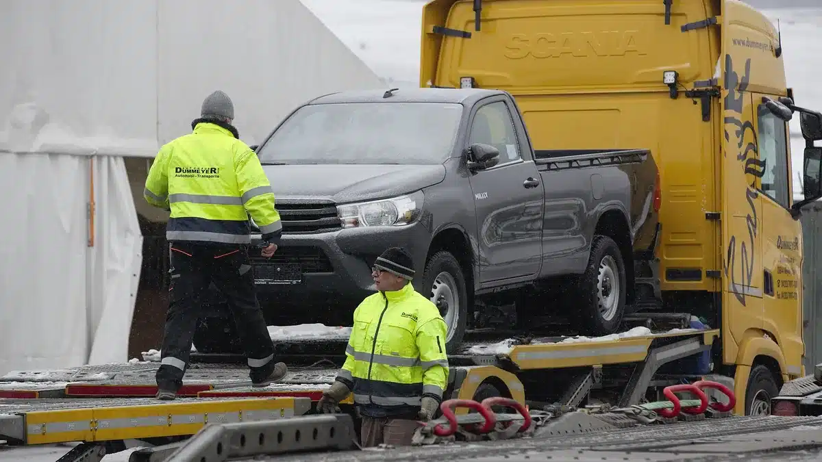 Transport crew unloading a pickup truck from a carrier at delivery